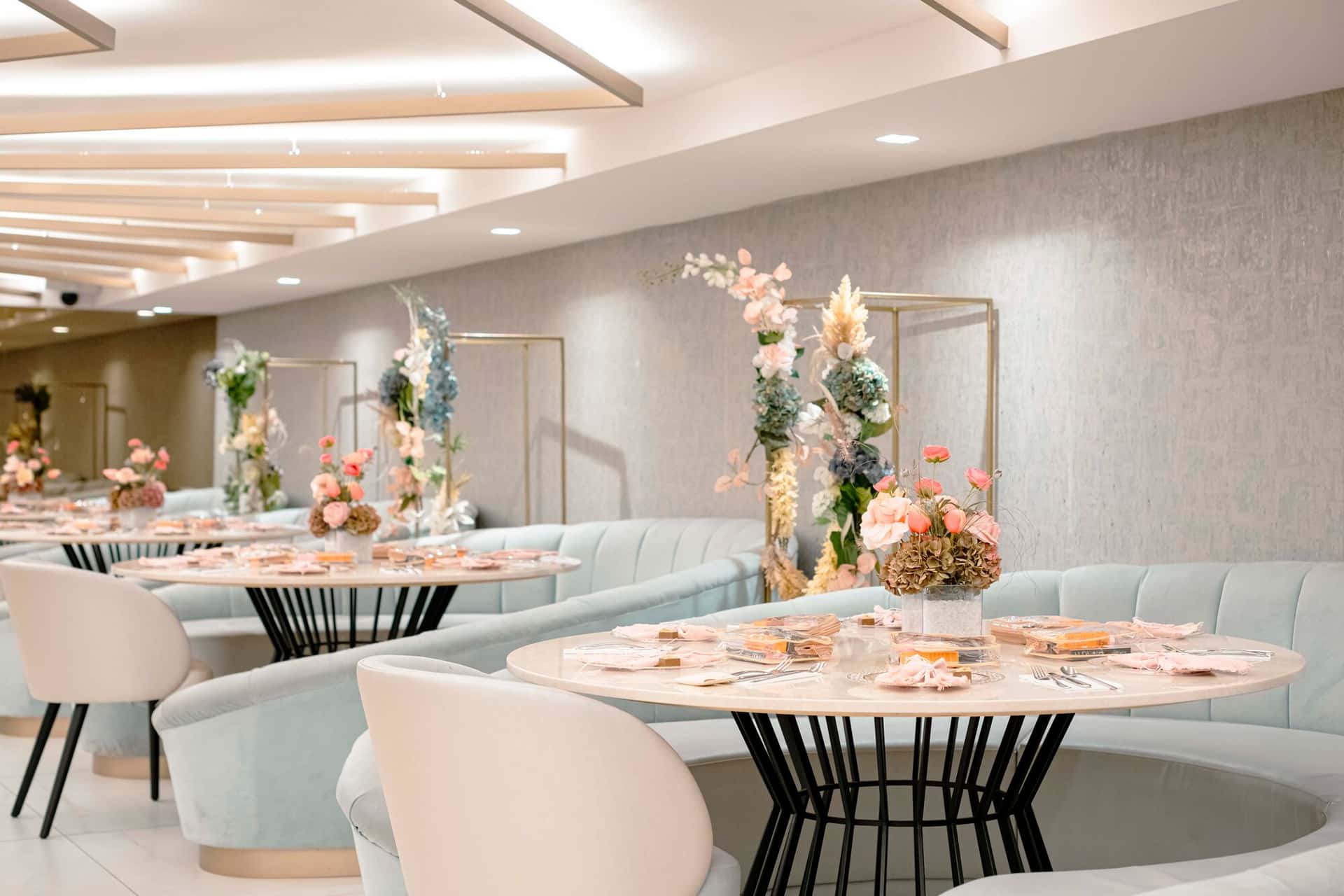A private dining room laid with marble tables, floral centrepieces and pale blue banquettes