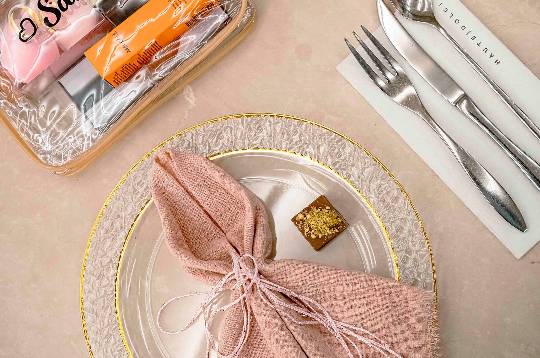 A place setting with a blush linen napkin, a gold-rimmed charger and a gold-flecked chocolate