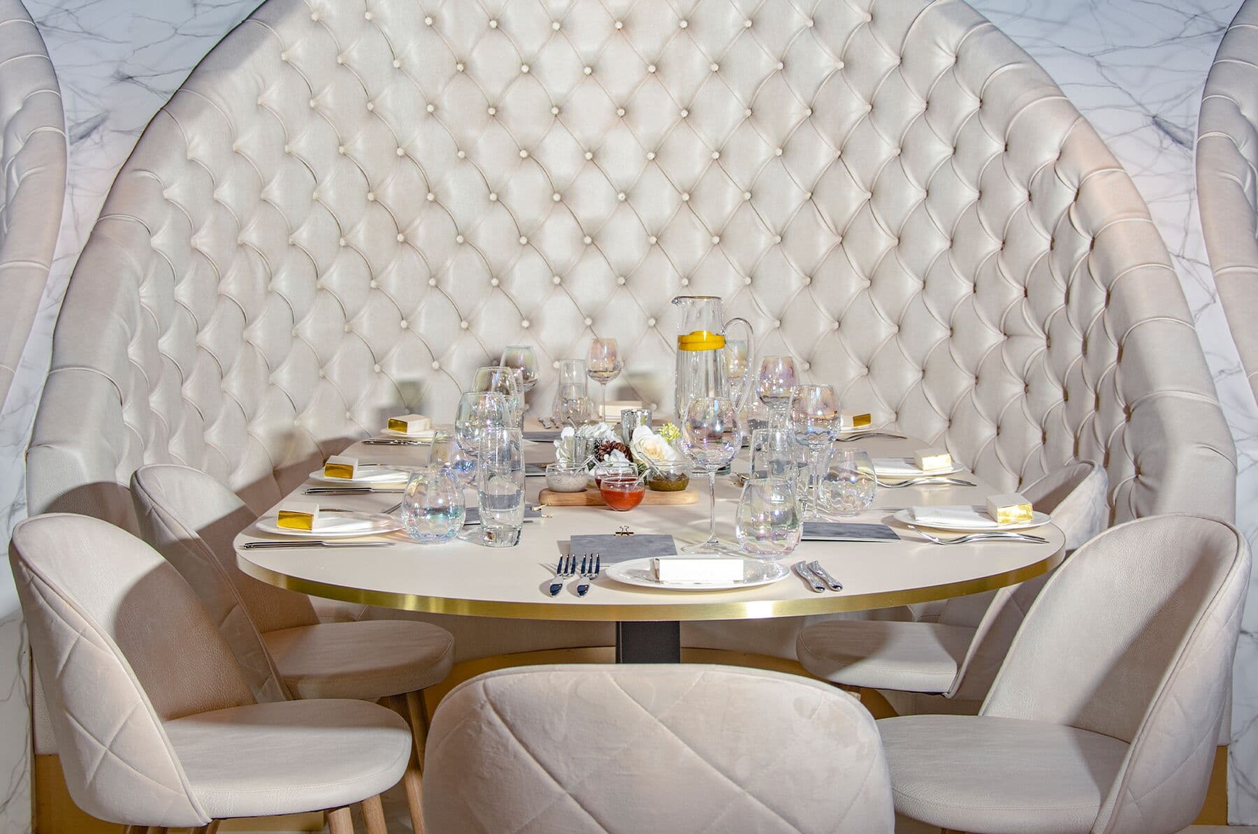 A round table laid for a meeting inside a cream quilted booth