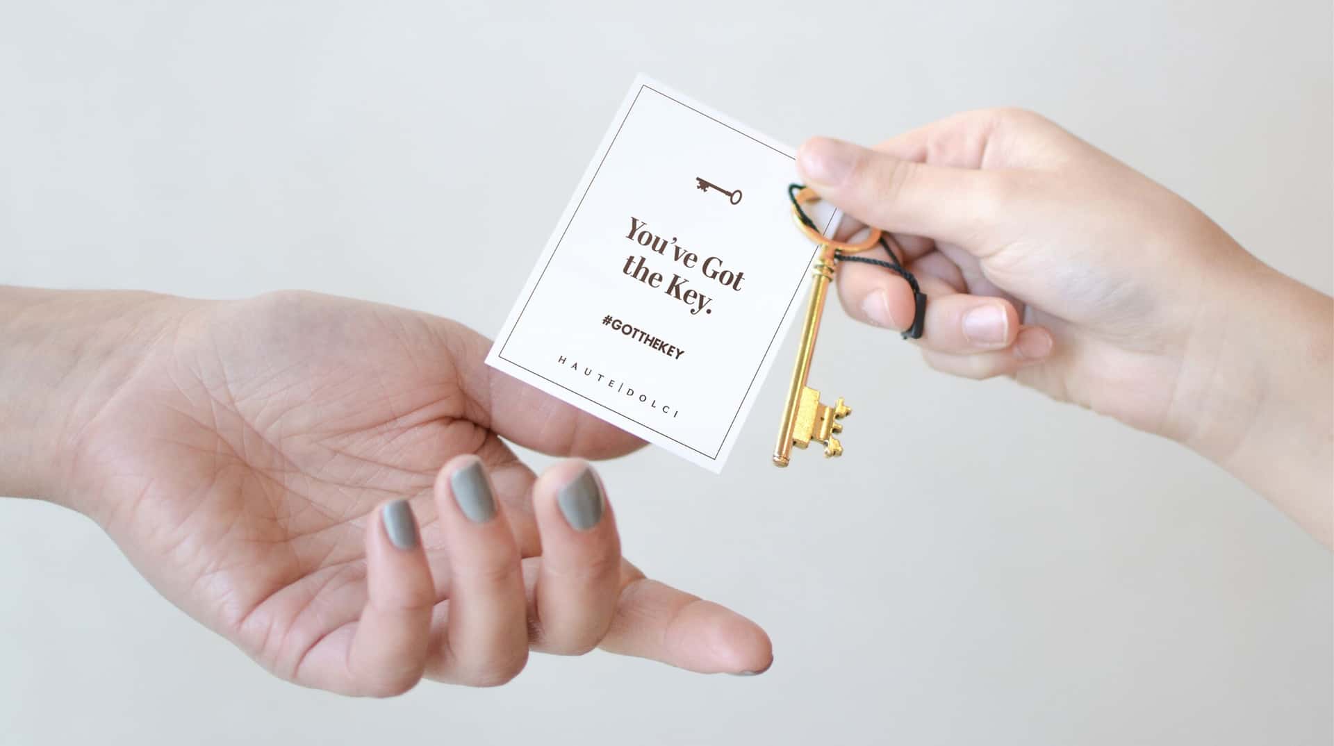 One hand passing another a golden HD Key tied to a “You've Got the Key” tag
