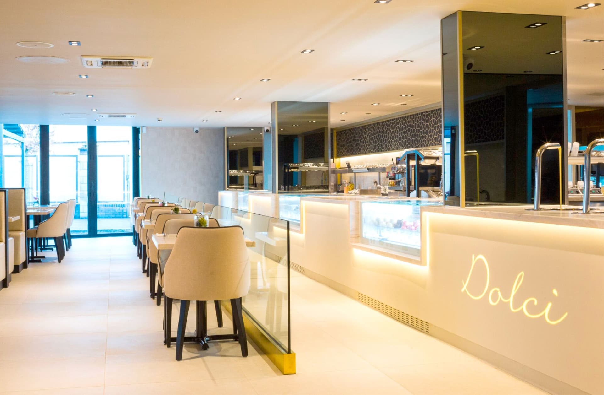 The first Haute Dolci at Cheshire Oaks: a long, softly lit dessert counter beside rows of cream dining chairs