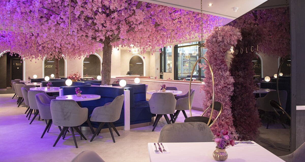 Haute Dolci Harrow under a canopy of lilac blossom trees, with grey velvet chairs and navy booths