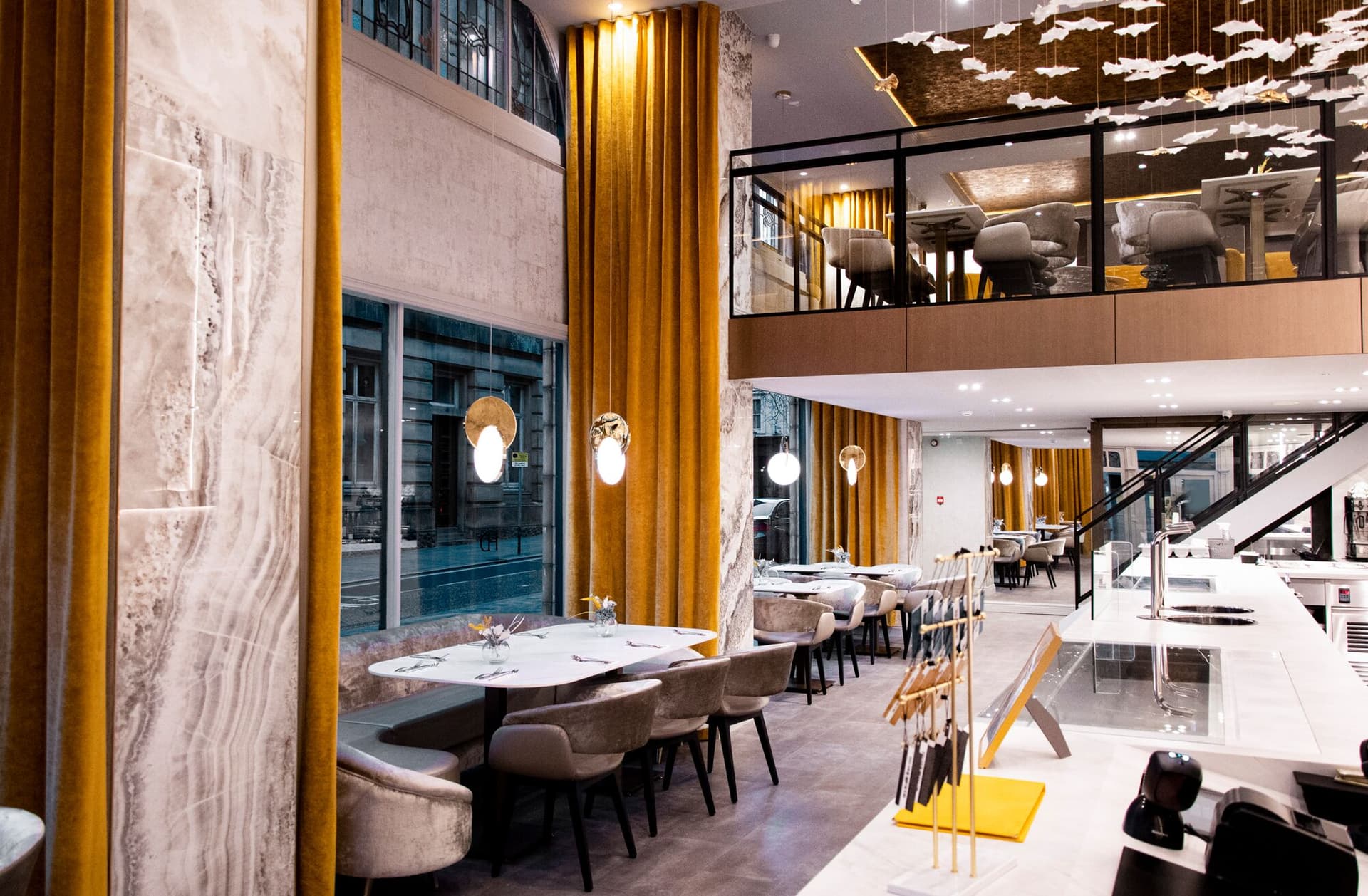 Haute Dolci Preston: onyx marble walls, ochre velvet curtains and a mezzanine under a flock of paper birds